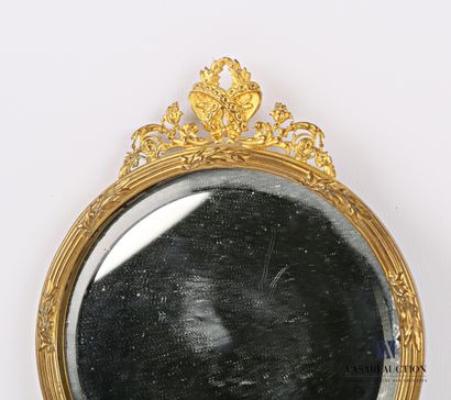 null Facing a bronze hand, the round bevelled mirror is set in a medallion hemmed...