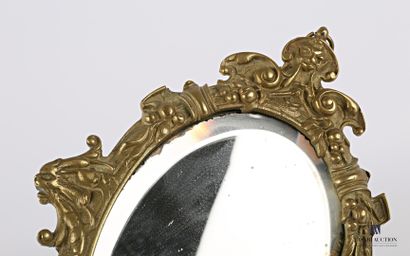 null Face to face in bronze, the bevelled oval mirror is set in a medallion hemmed...