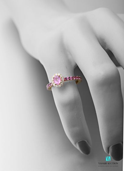 null 750 thousandths yellow gold ring set with an oval-shaped pink sapphire calibrating...
