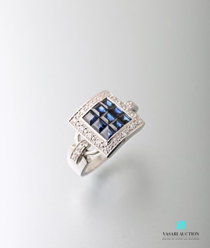 null A 750 thousandths square white gold ring centered on nine princess cut sapphires...