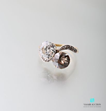 null A 750 thousandths yellow gold ring set with two main old cut diamonds: one white...