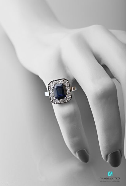 null 750-thousandths white gold ring set with an emerald-cut sapphire calibrating...