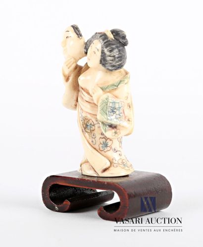 null Netsuké en ivoire figurant une courtisane seins nus tenant dans sa main droite...