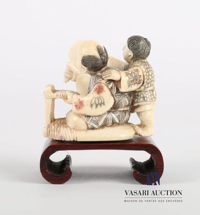 null Netsuke en ivoire à décor polychrome représentant un homme assis en tailleur...