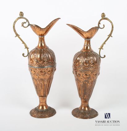 Two ewers in embossed copper, the body decorated...