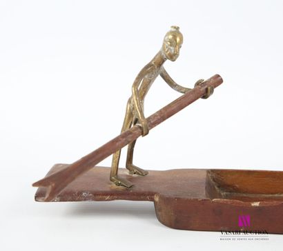 null A wooden and bronze penholder depicting a pirogue with two paddling figures.
(one...