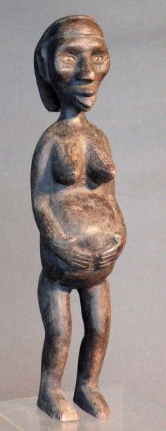 null Statuette en bois à patine sombre figurant une femme enceinte debout, le visage...