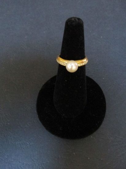  Bague en or jaune ponctuée d’une perle 
de culture Akoya de 7 mm, encadrée de deux...