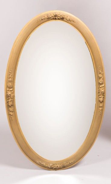 null Miroir de forme ovale en bois et stuc mouluré et sculpté à décor de cannelures...