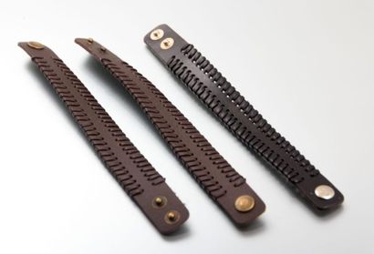 null Trois bracelets en cuir bruns, les côtés ajourés et cousus d'un fil de cuir....