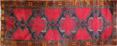 null Tapis en laine à décor de médaillons sur fond rouge 
(usures)
310 x 117 cm