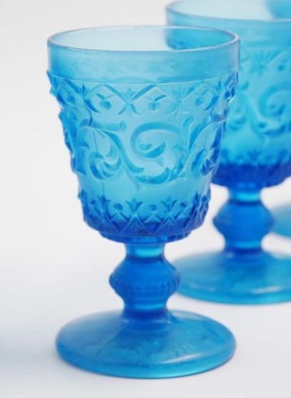 null Glasses chalices on pedestal in moulded blue glass with decoration of volutes...