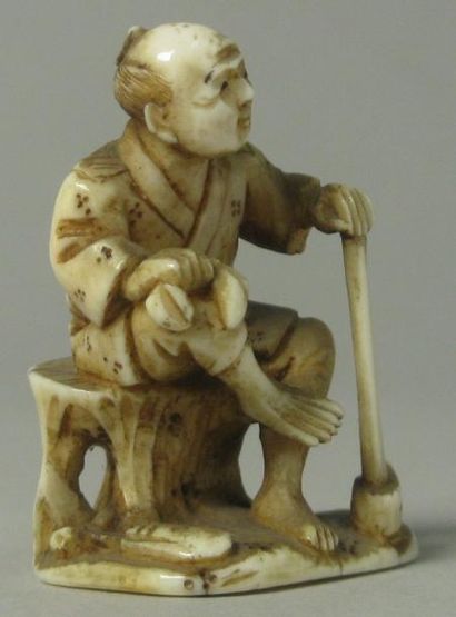 JAPON Netsuke en ivoire représentant un homme assis avec une hache. H: 4 cm. Etiquette...