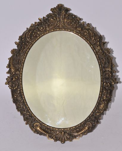 Miroir ovale en métal sculpté et doré à décor...