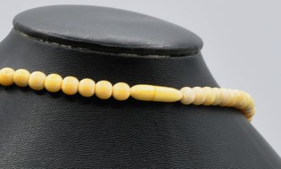 null Long collier pendentif boules en ivoire se terminant par un médaillon ovale...
