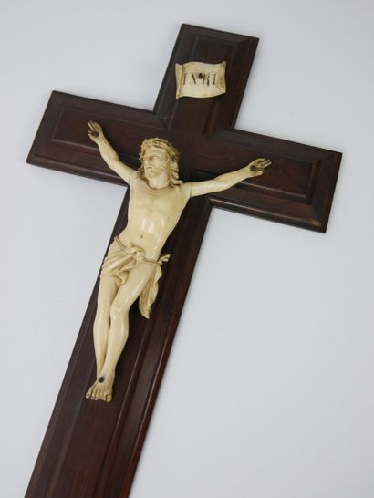 null Christ en os sculpté, présenté sur une croix en bois et surmonté d'une plaquette...