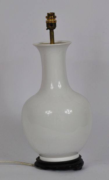 null Vase de forme balustre en porcelaine blanche reposant sur un socle en bois sculpté....