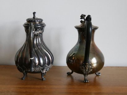 null Two silver plated metal and blackened wood teapots. The first one resting on...