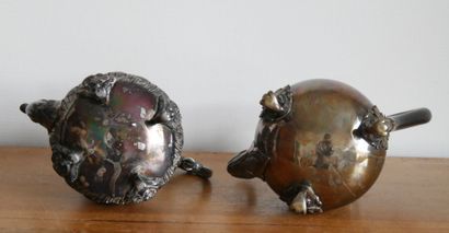 null Two silver plated metal and blackened wood teapots. The first one resting on...