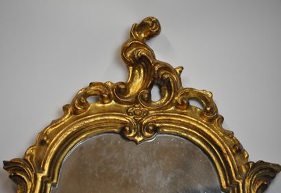 null Miroir en bois sculpté et doré de forme violonnée à décor de coquilles et fleurettes....