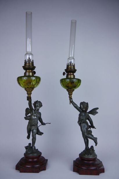 null Pair of silver-plated metal oil lamps decorated with winged putti resting on...