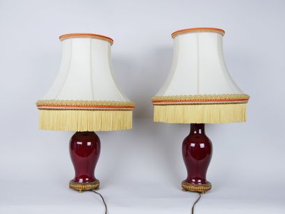 null Pair of enamelled porcelain lamps, color said "oxblood", resting on a gilded...