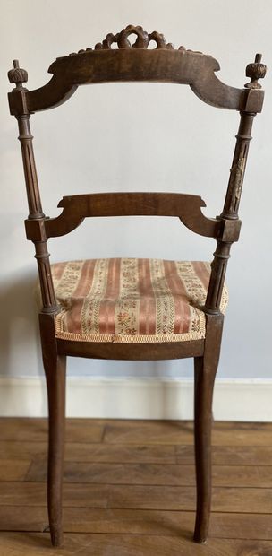 null Pair of carved wood chairs with a barred backrest topped by a ribboned bow resting...