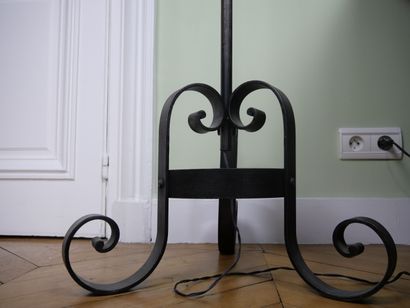 null Wrought iron floor lamp decorated with scrolls resting on a tripod base with...