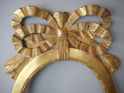 null Oval frame in carved and gilded wood, topped with a large ribbon knot, and palms.

19th...