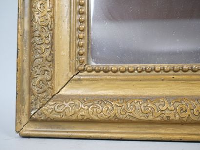 null Miroir en bois redoré de forme cintrée à décor de frises de perles et de rinceaux....
