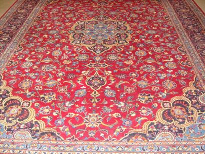 IRAN Grand tapis à médaillon central sur fond rouge. 418x287cm