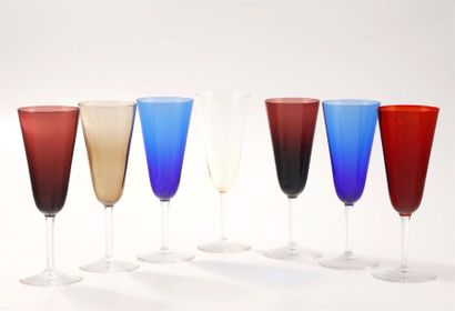 null Seven glass Champagne flutes of different colours on a transparent base.