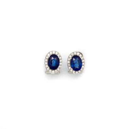 null Pair of white gold ear clips with sapphires of approximately 3 carats and surrounded...
