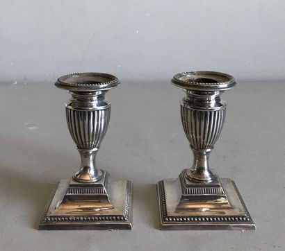 null Pair of small silver plated metal candleholders with fluted shaft resting on...
