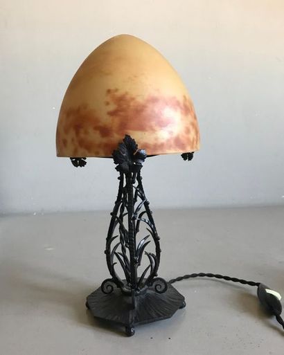 null Wrought iron lamp with openwork foot, surmounted by a marmoreen glass lampshade....