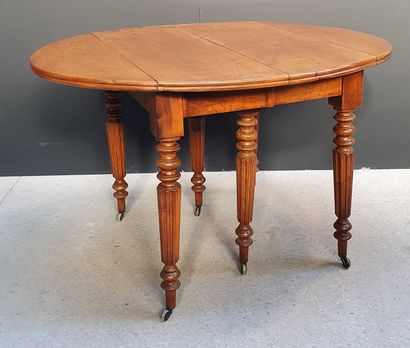 null Oval dining room table in natural wood with two flaps resting on six fluted...