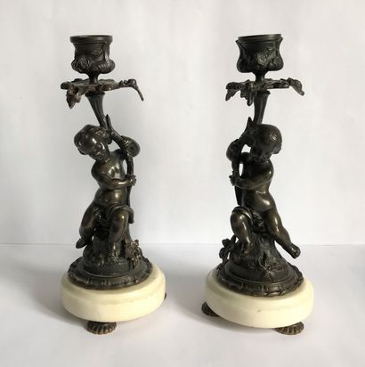 null Pair of candlesticks in patinated bronze with two Putti (boy and girl) holding...