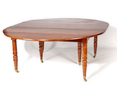 null A large solid mahogany dining room table of circular form, resting on double...