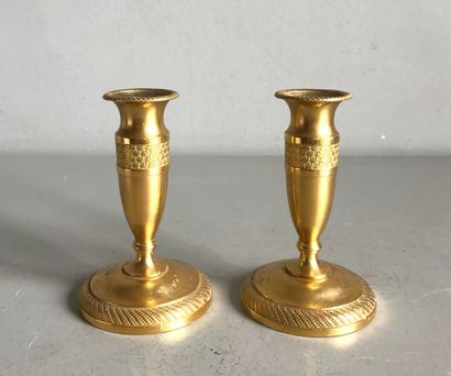 null A pair of small ormolu candlesticks chased with piastres and twisted flutes.

Empire...