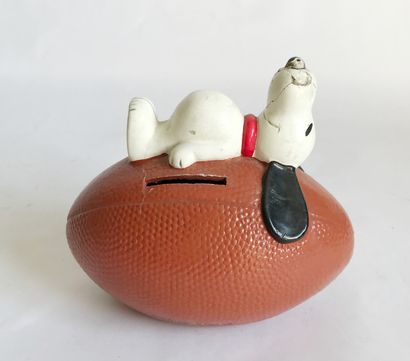 null Plastic money box (?) representing Snoopy lying on a rugby ball

H. 11 - L 12...