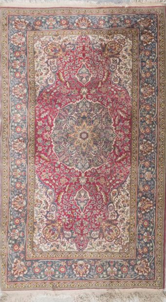 null Polychrome wool carpet, the field decorated with a flowery rosette on a red...