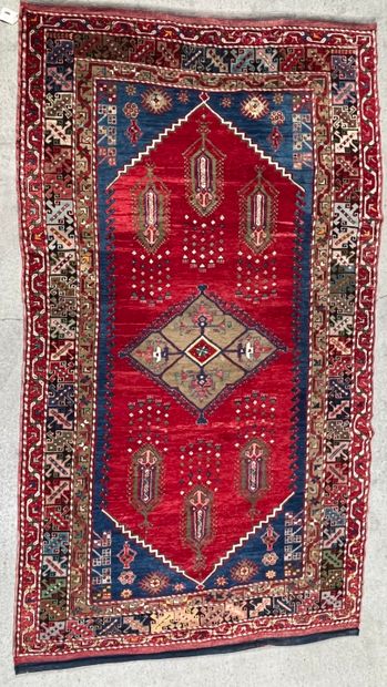 null Woolen carpet with central medallion and six motifs with pendants on red field....
