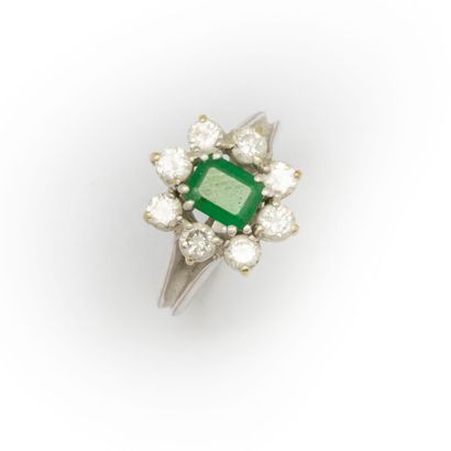 null 18K white gold ring set with a rectangular cut emerald in a setting of eight...
