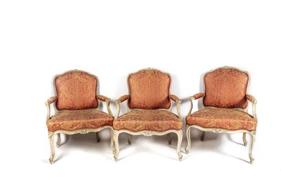 null Suite de trois fauteuils en bois laqué crème, mouluré et sculpté de fleurs....