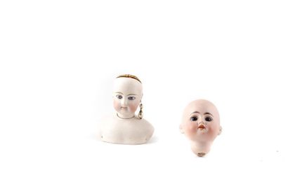 null Lot de 2 têtes de poupée en porcelaine, yeux immobiles. 
H. 11 cm 