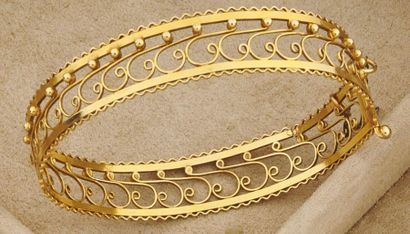 null *Bracelet rigide ouvrant en or jaune 750 millièmes ajouré à décor d'enroulement...
