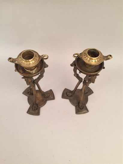 null Pair of bronze selettes decorated with wolf heads, bearing flamed pots. Signed...