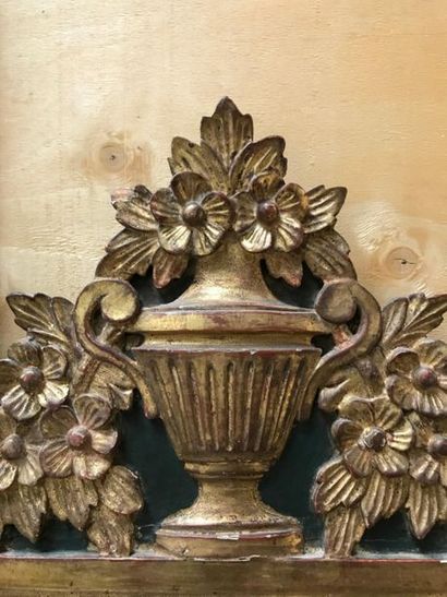 null Petit miroir à fronton en bois et stuc dorés surmonté d'un vase fleuri. Vers...