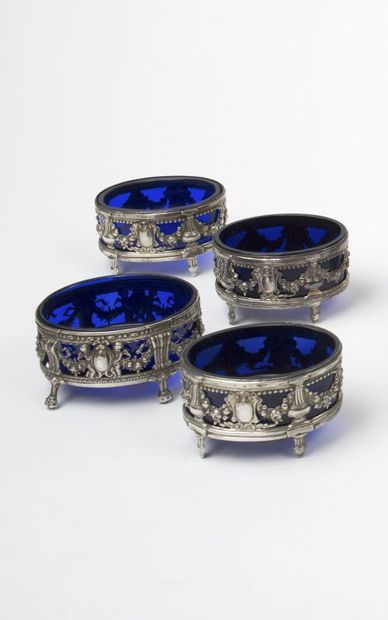 null A SET of four silver salerons, standing on four fluted legs, with repoussé decoration...