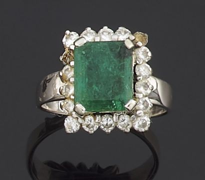 null Silver ring set with a rectangular emerald in a circle of round brilliant-cut...